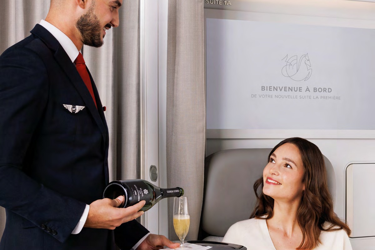 Air France La Première crew pouring champagne for passenger in suite, Suite 1A visible