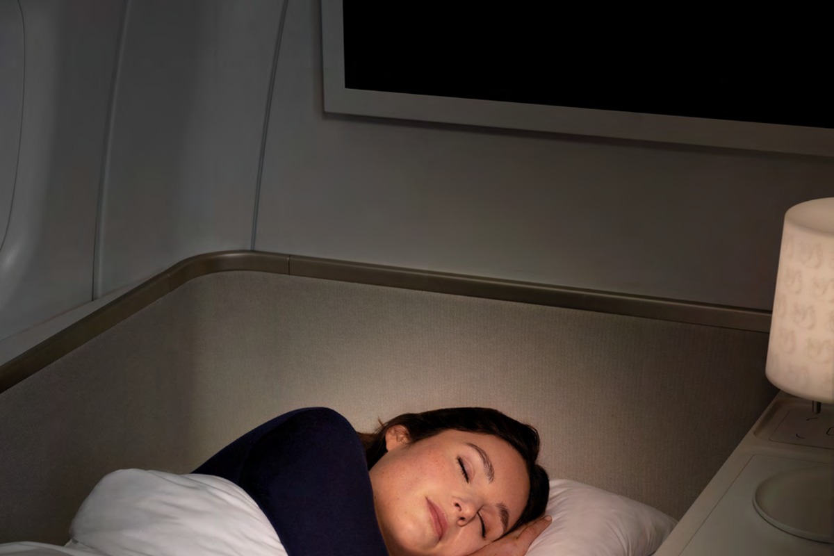 Passenger sleeping in Air France La Première fully flat bed — two metres, Dumas Paris duvet, personal lamp
