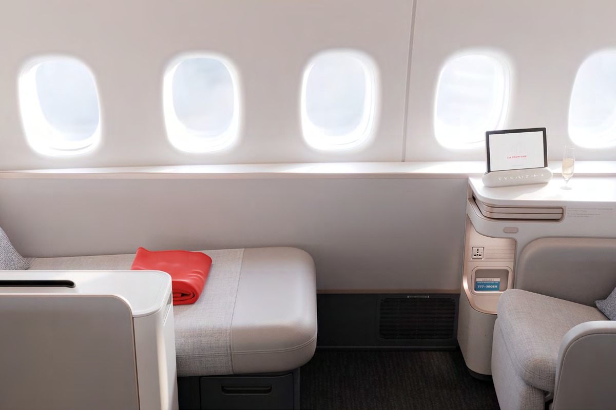 Air France La Première cabin showing paired centre suites with five windows, grey upholstery and red blanket